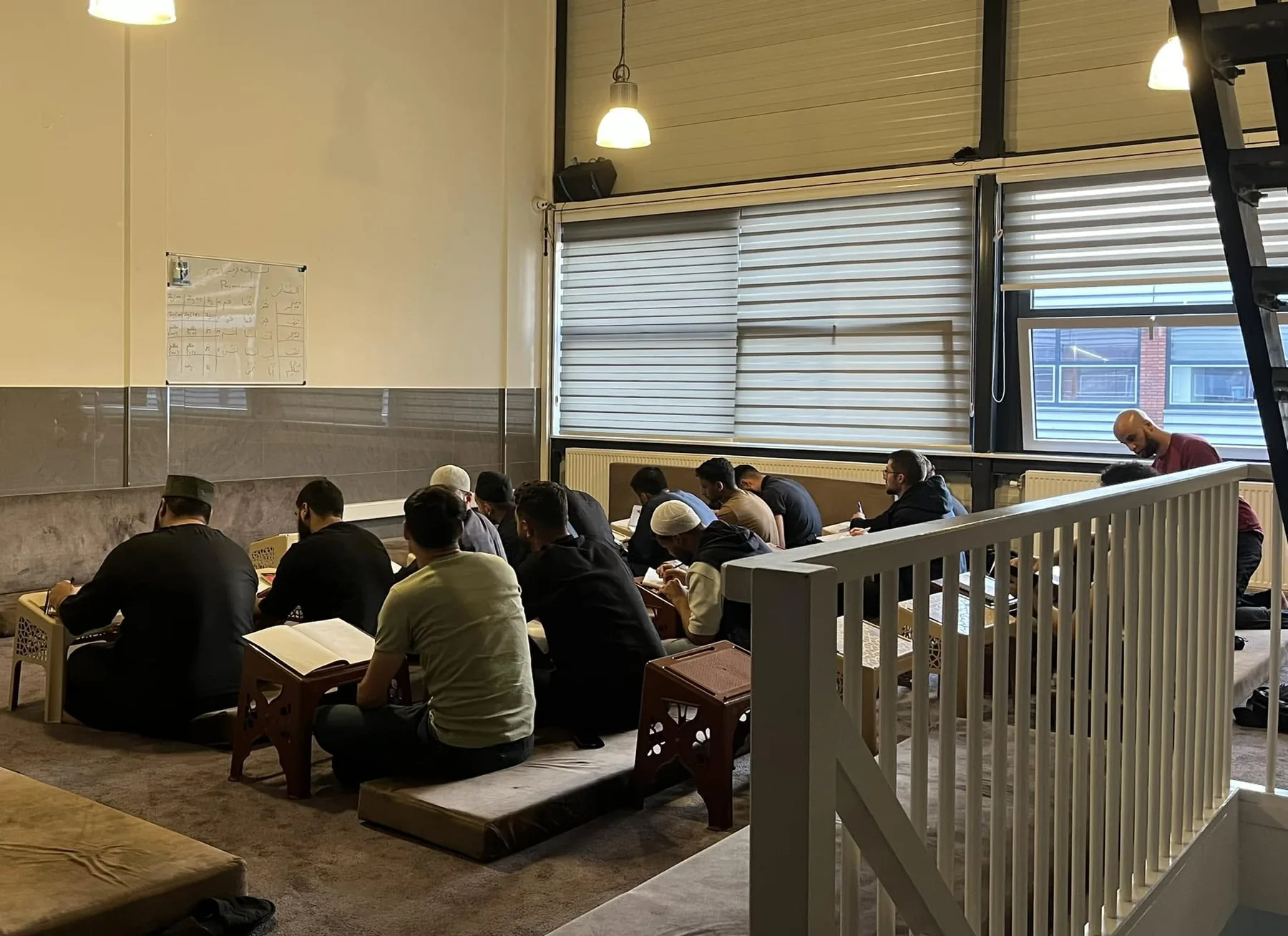 Studenten zitten op de vloer met boeken op houten leesstandaards tijdens de les